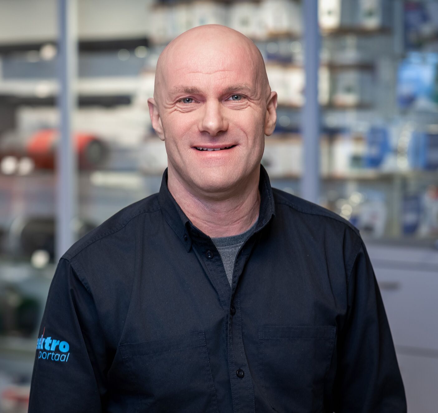 Portret van een medewerker van Elektroportaal in bedrijfskleding, staand in de winkel.