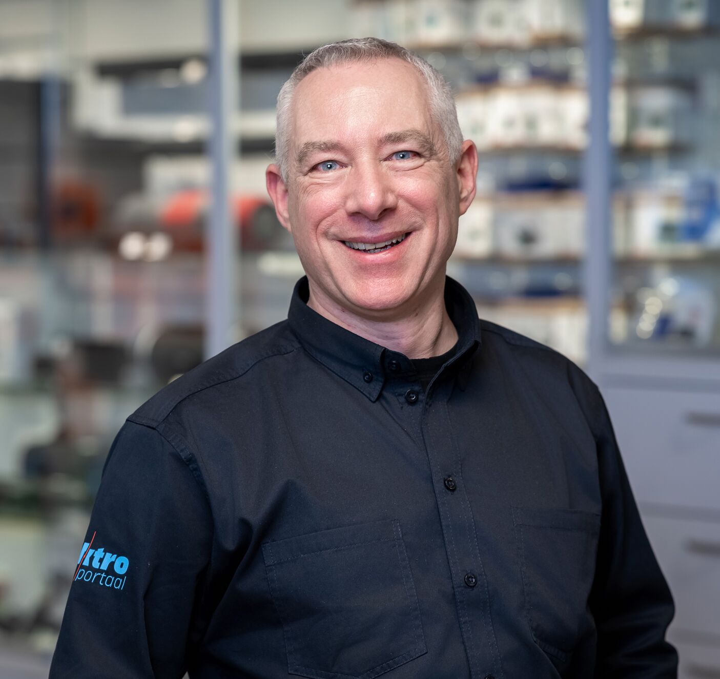 Portret van een medewerker van Elektroportaal in bedrijfskleding, glimlachend in de winkel.