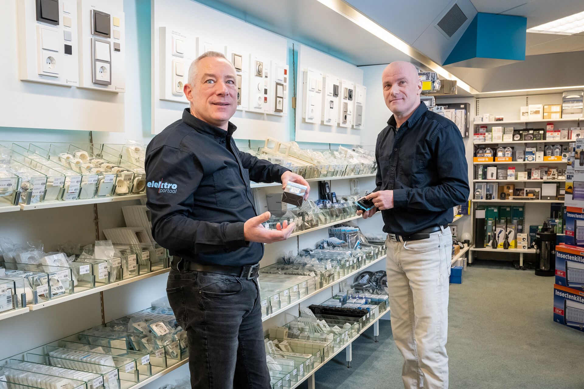 Medewerkers van Elektroportaal in de winkel, omringd door schakelmateriaal en elektrische producten.